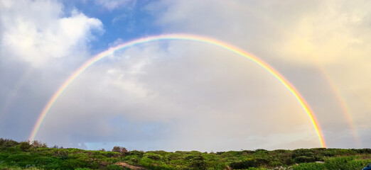 Fototapeta na wymiar Rainbow in blue sky shot in Kamay Botany Bay National Park