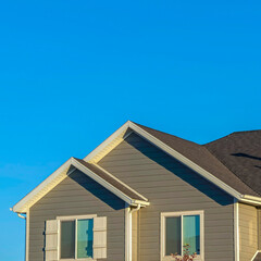 Square frame Home exterior with view of the upper storey agaist clear blue sky background