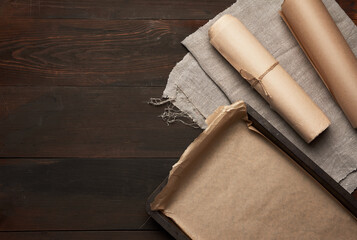 empty rectangular metal pan covered with brown parchment paper and paper rolls