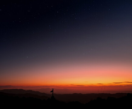 Precioso anochecer en la cima de una montaña con colores cálidos y un cielo estrellado