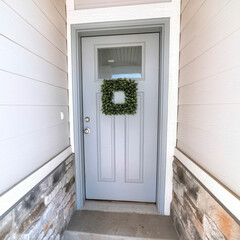 Square frame Square leafy wreath on front door entrance with glass pane and transom window