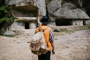 A young male traveler explores the ruins of a cave city in the mountains. Active tourism