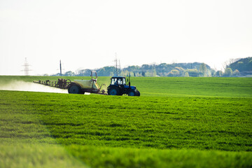 Fototapeta na wymiar Tractor spraying pesticides on field with sprayer at summer