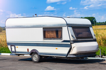 Old white trailer van against the background of a field with yellow grass and trees mobile motorhome for the whole family to travel on a summer day.