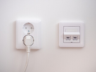 Electrical sockets on the wall with black connection internet plug and white wire.