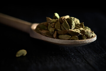 Cardamom grains in a wooden spoon.