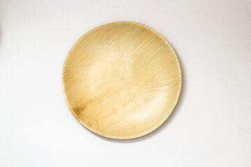 Round Areca Leaf Plate, eco-friendly disposable cutlery. Top view on a white background.