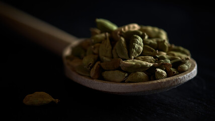 Cardamom grains in a wooden spoon.