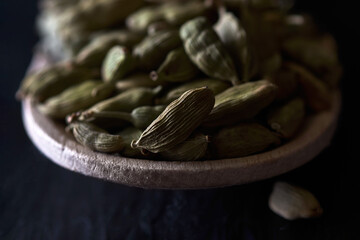 Cardamom grains in a wooden spoon.
