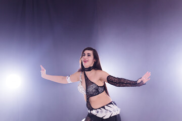 Fototapeta na wymiar Young woman belly dancer in exotic dress with gold, dancing tribal fusion dance in studio.