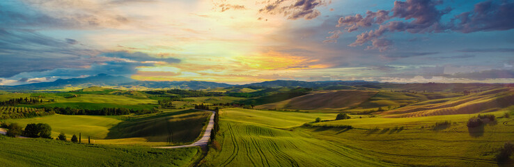 Amazing colorful sunset in Tuscany. Picturesque agrotourism and typical curved road with cypress, landscape in Tuscany, Italy, Europe