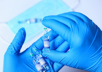 Coronavirus COVID-19. Ampoule with single dose of experimental vaccine. Scientist's hand in latex...