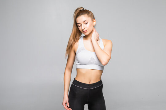 Young sport woman in a fitness outfit experiencing neck isolated on white background