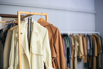 Lot of clothes hangers that are closely located next to each other in a store with women's clothing. Atmosphere of women's space, small showroom with minimalistic clothes for summer and fall.