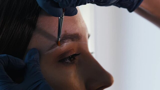 Brow master cleaning the markup on the eyebrows of a model