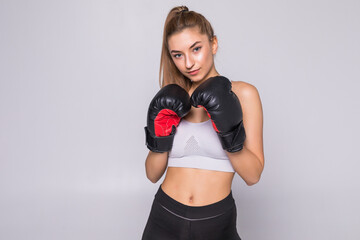 Beautiful smiling young fitness woman wears boxing gloves over white background