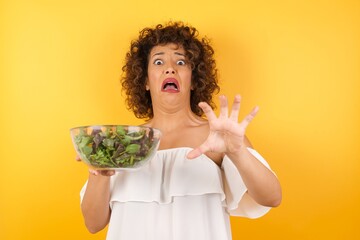 Dissatisfied female model frowns face, has disgusting expression, shows tongue, expresses non...