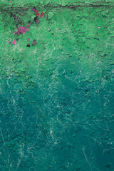 Obraz premium The texture of cracked green paint in different shades with pink spots and white stains. The vertical photo for your urban design.