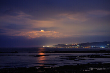 Fototapeta premium Moon rise over coastal city