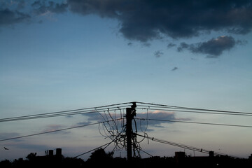 cluster electric pole with wires background dark clouds with sillhoutte