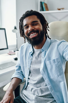 Charming Young African Man Smiling And Looking At Camera While Taking Selfie Indoors