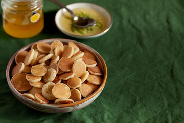 Bowl with tiny pancake cereal porridge on a green textile background with copy space.Trendy tasty breakfast food
