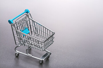 Metal shopping cart (toy). Gray background, copy space.