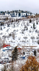 Vertical crop Park City neighborhood on snowy hill brightened by colorful homes and evergreens