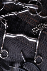  various bits  with mouthbridle on black wooden  background. flat lay
