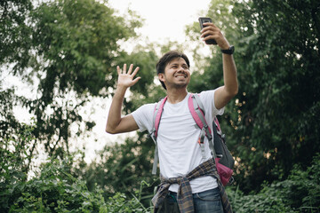 Young Asian man traveling backpacker making selfie in the forest, Concept of nature tourism
