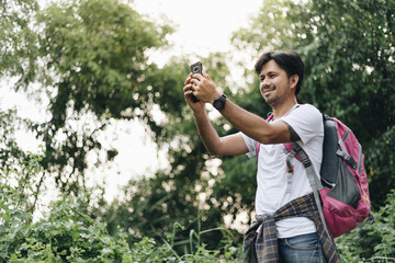 Young Asian man traveling backpacker making selfie in the forest, Concept of nature tourism