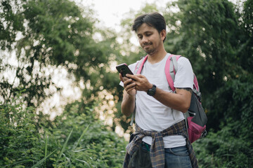 Young asian man traveler using smartphone in forest, Concept of nature tourism