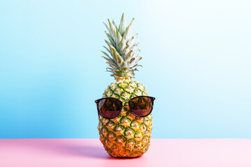  Fresh ripe pineapple in glasses on a pink and blue background. summer concept, minimalism, copy space.