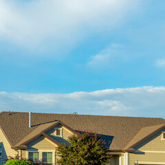 Square Gray roof of sunlit home with vast cloudy blue sky background on a sunny day
