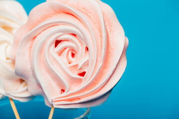 Beautiful tender meringue on a stick in a glass on a blue background, March 8, Mom day, birthday present, sweets.