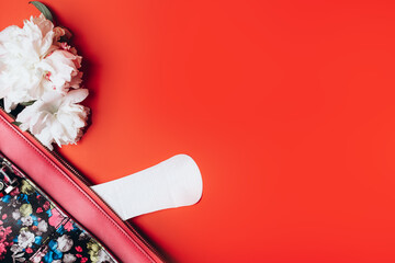 sanitary napkin stick out from the bag and in the corner are beautiful peonies on a red background,...
