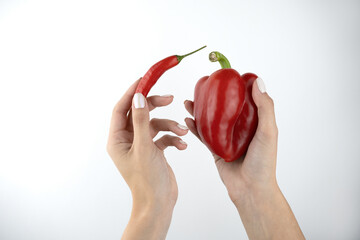 image of woman's hands holding red fresh chilly pepper and sweet red pepper on isolated white background