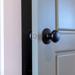 Square frame Gray paneled hinged wooden bedroom door with black door knob and visible latch