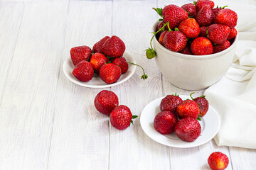 Large ripe strawberries are collected from the garden. On a white wooden background. Homemade winter fruit blanks. Selective focus.