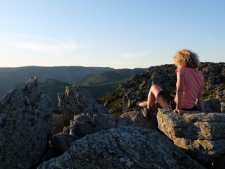 Jeune femme blonde seule face au soleil couchant en montagne tranquillité luxe calme et volupté dans le Parc Naturel régional du Caroux Haut Languedoc