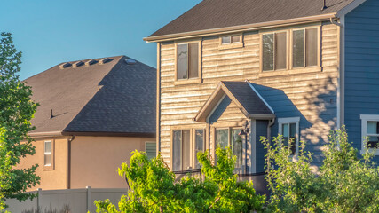 Panorama Sunny day view of home exterior with gray roof over sunlit wall and windows