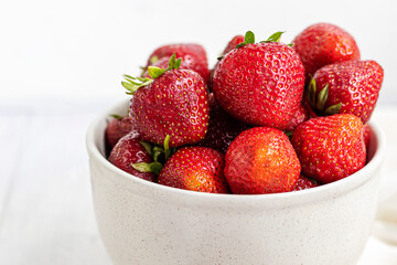 Large ripe strawberries are collected from the garden. On a white wooden background. Homemade winter fruit blanks. Selective focus.