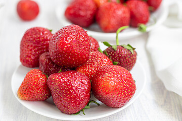 Large ripe strawberries are collected from the garden. On a white wooden background. Homemade winter fruit blanks. Selective focus.