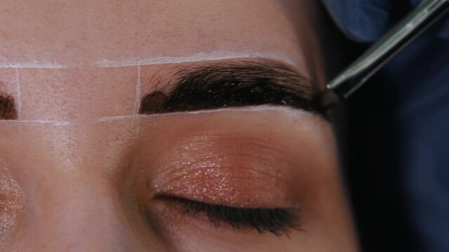 Brow master filling in the eyebrow with brown hair dye for the brows