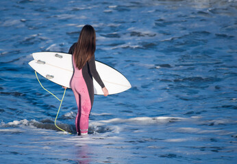 girl surfing on the shore of the beach, with surfboard, with sea in the background