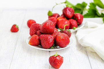 Large ripe strawberries are collected from the garden. On a white wooden background. Homemade winter fruit blanks. Selective focus.