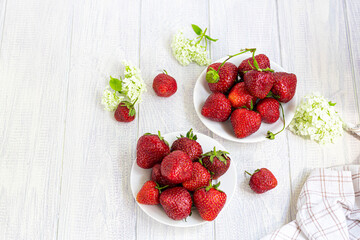 Large ripe strawberries are collected from the garden. On a white wooden background. Homemade winter fruit blanks. Selective focus.