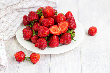Large ripe strawberries are collected from the garden. On a white wooden background. Homemade winter fruit blanks. Selective focus.
