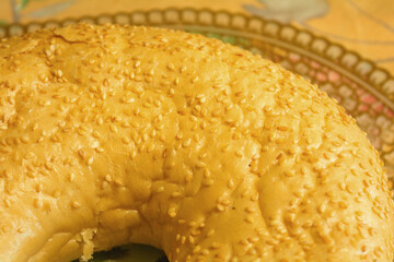 Big bagel with sesame seeds close-up on a decorative background with gold lace