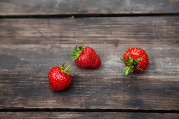 
Three strawberries on a rustic wooden table. home grown strawberries